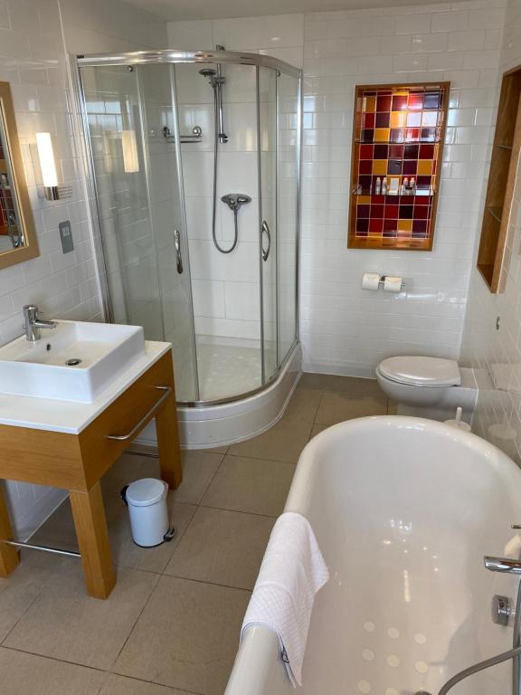 a bathroom with a tub and a sink and a shower at The Brudenell in Aldeburgh