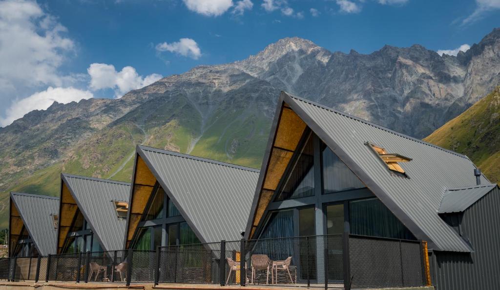 a building with a mountain in the background at Kazbegi Targmani Cottages in Kazbegi