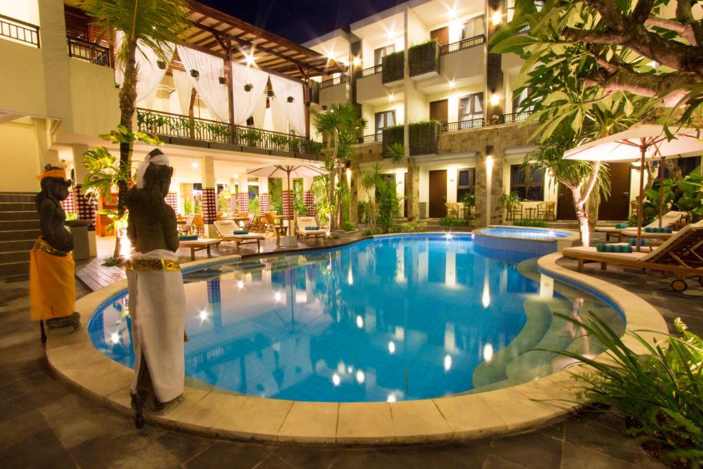 a hotel swimming pool with two people standing next to it at Manggar Indonesia Hotel in Kuta