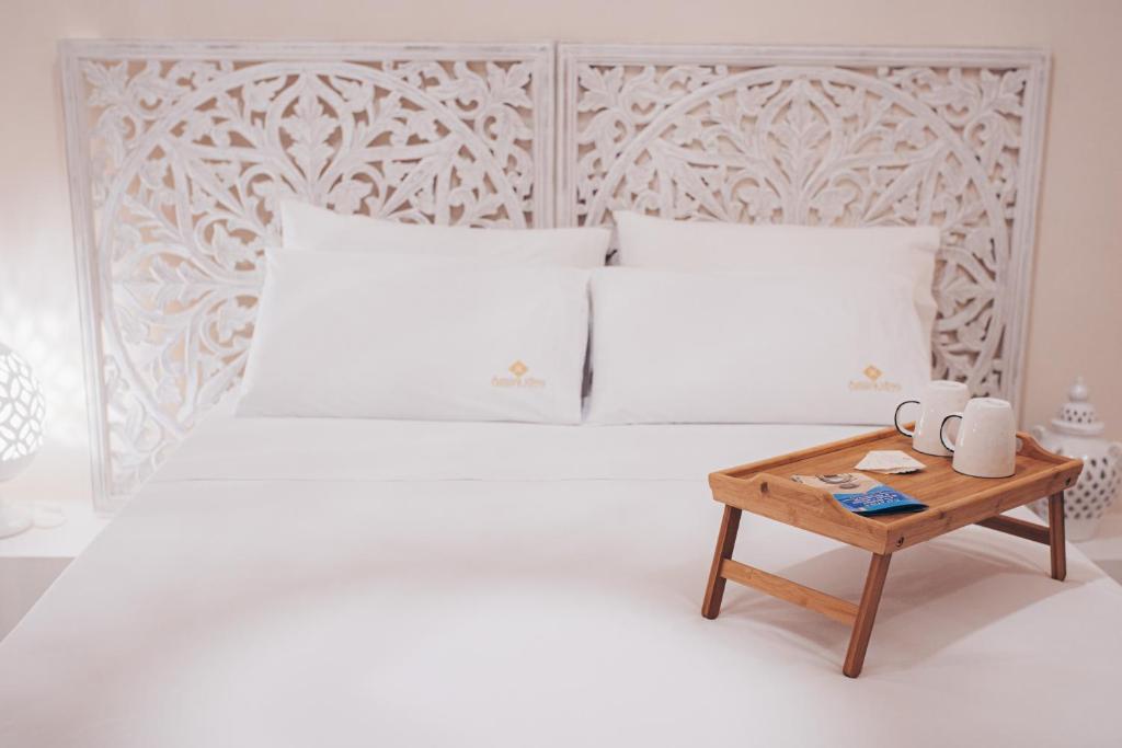 Amira 1899 Luxury Suite في غالاتينا: غرفة نوم بيضاء مع سرير أبيض وطاولة خشبية