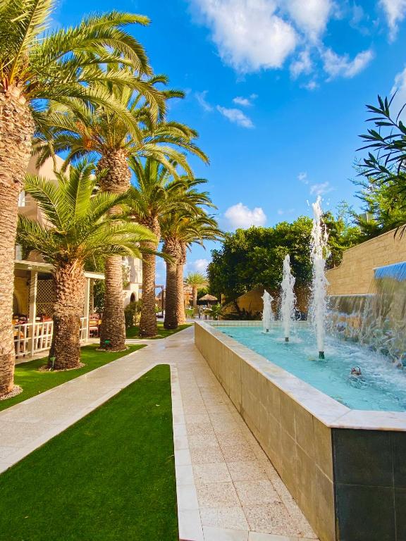 a fountain in a park with palm trees at Karteros Hotel in Karteros