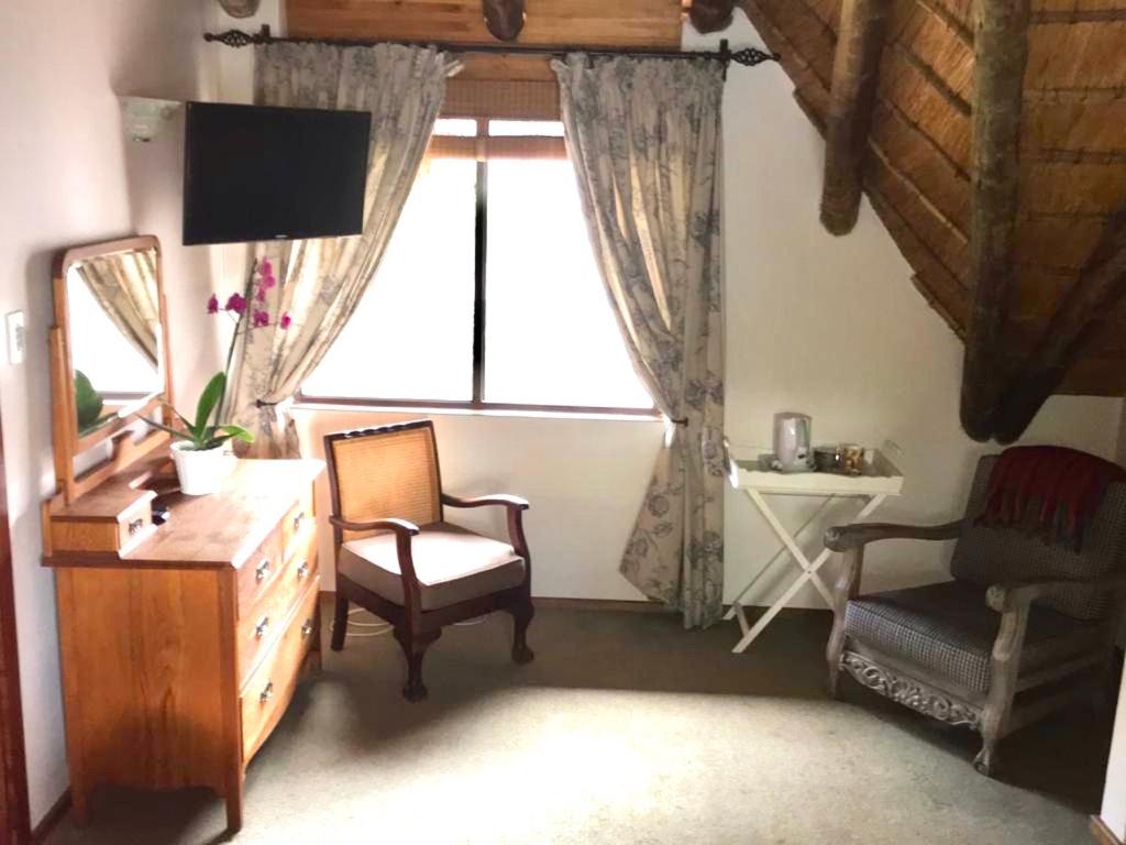 uma sala de estar com uma cadeira, uma cómoda e uma janela em Du Barry Guest House em Pretoria