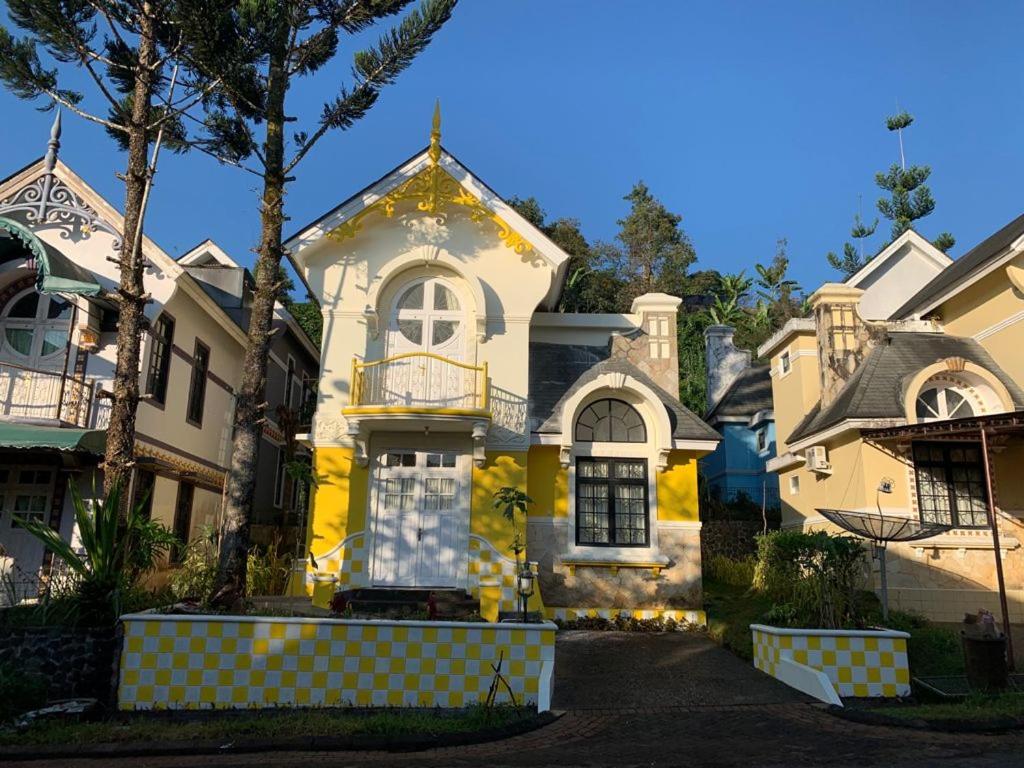 a yellow and white house with a tree at Villa Wubao Kota Bunga 3 Kamar Harga Budget in Cinengangirang