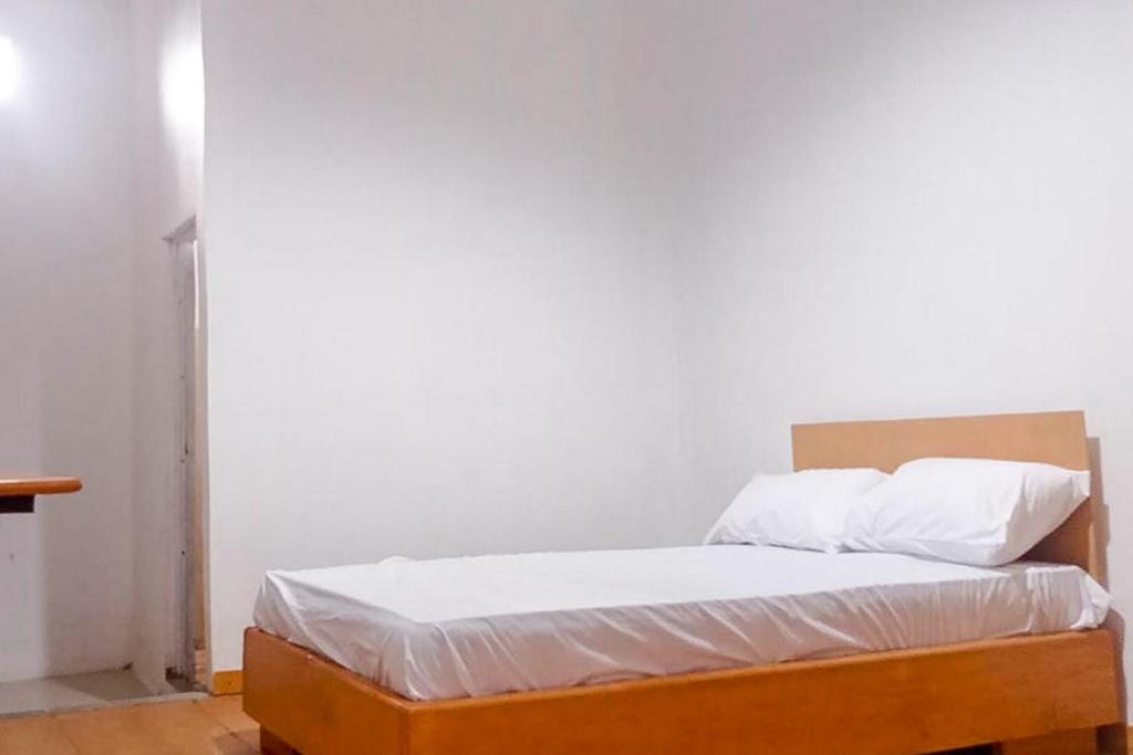 Bett in einem Zimmer mit einer weißen Wand in der Unterkunft Cangguhos Syariah RedPartner in Tanjungkarang