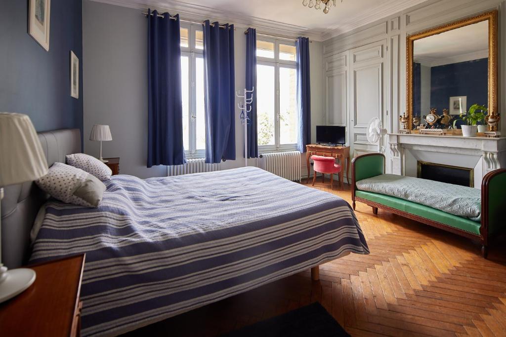 a bedroom with a bed and a chair and a fireplace at L'Antre de Gadag in Forges-les-Eaux