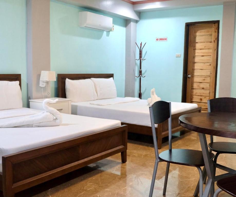 a room with two beds and a table and chairs at Keyun's Inn- Across Cloud 9 in General Luna