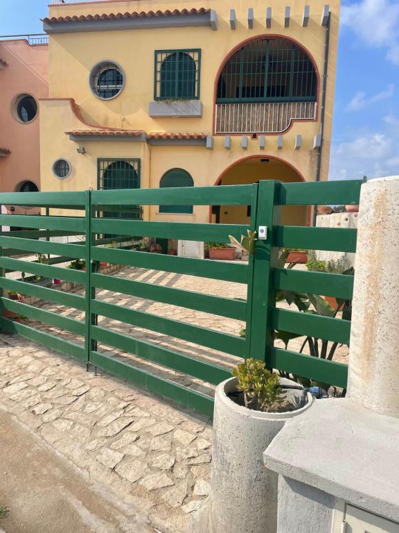 une clôture verte devant un bâtiment dans l'établissement Appartamento Marzamemi, à Marzamemi