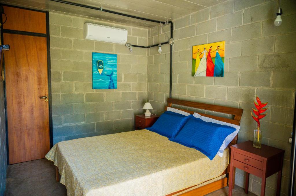 a bedroom with a bed and two paintings on the wall at Casa do Pescador Camburi in Camburi