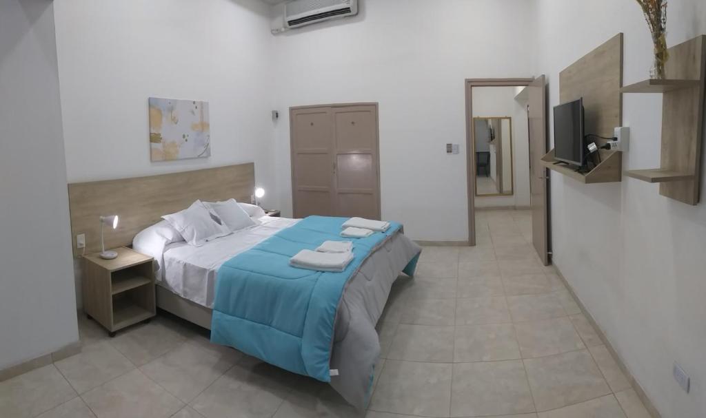 sypialnia z łóżkiem z niebieską pościelą i telewizorem w obiekcie Multiespacio Center w mieście San Fernando del Valle de Catamarca