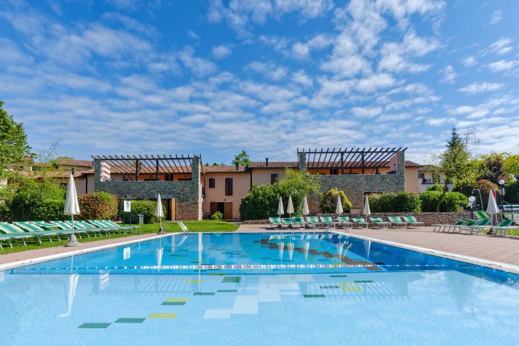 duży basen z krzesłami i budynek w obiekcie Golf Residenza w mieście Peschiera del Garda