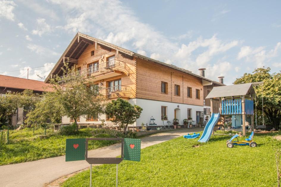 ein Haus mit einem Spielplatz vor einem Gebäude in der Unterkunft Ferienparadies Reifnhof in Riedering