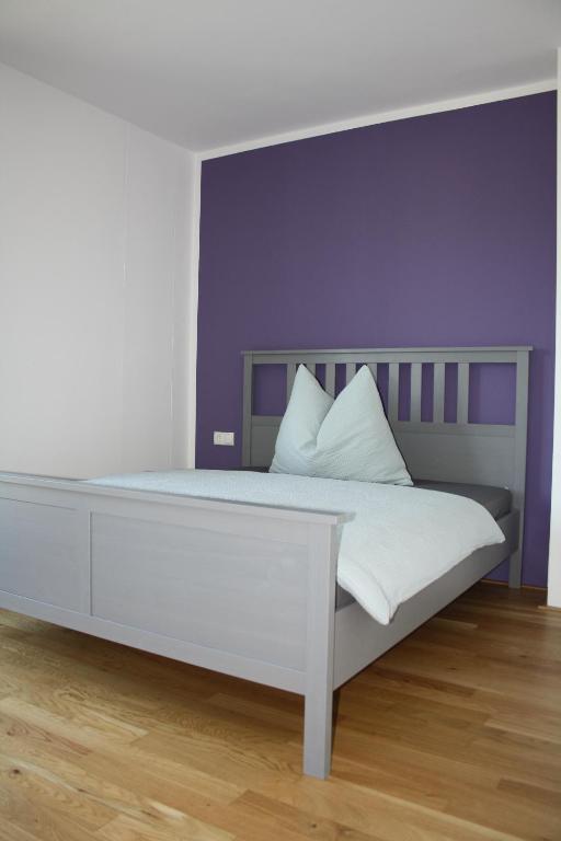 um quarto com uma cama com uma parede roxa em Felseck Zimmer em Innsbruck