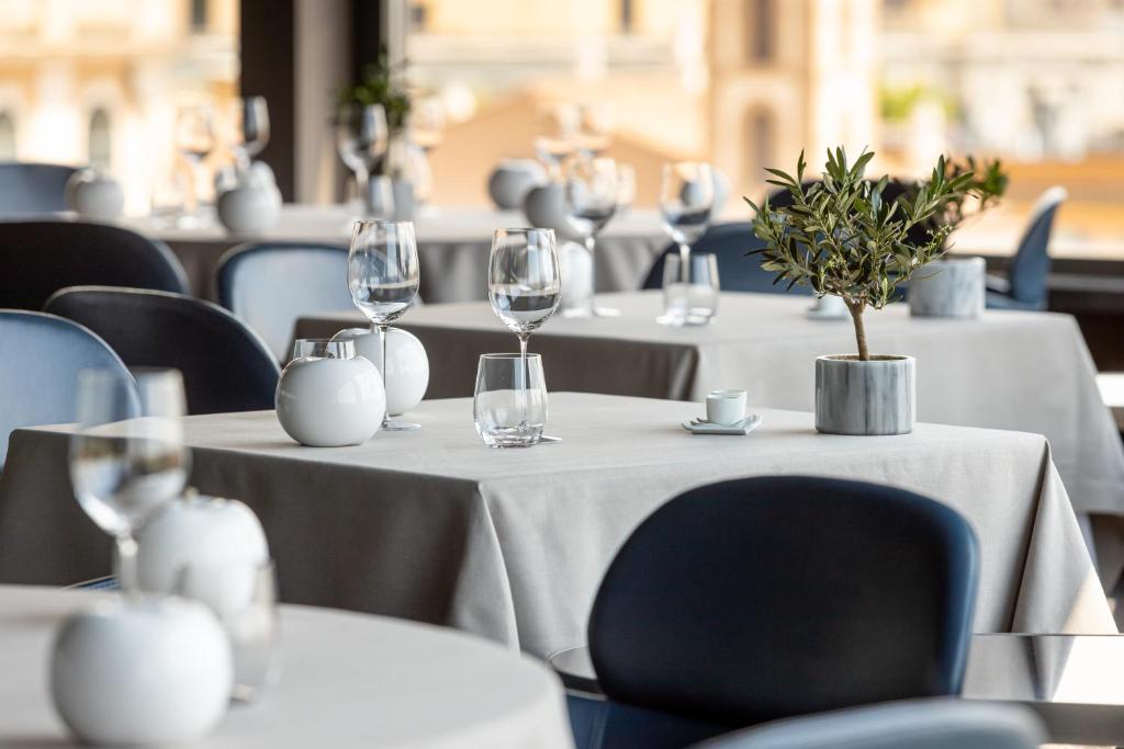 a row of tables in a restaurant with wine glasses at Hotel Eden - Dorchester Collection in Rome