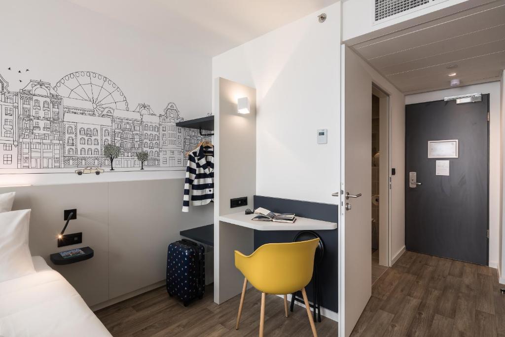 a bedroom with a bed and a desk and a yellow chair at B&B Hotel Budapest City in Budapest