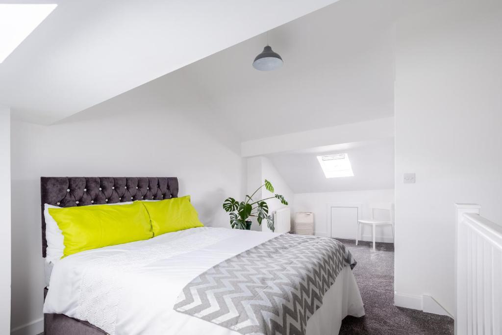 a white bedroom with a large bed with yellow pillows at Whole house in centre of Town Ideal for Contractors and Professionals in Normanton