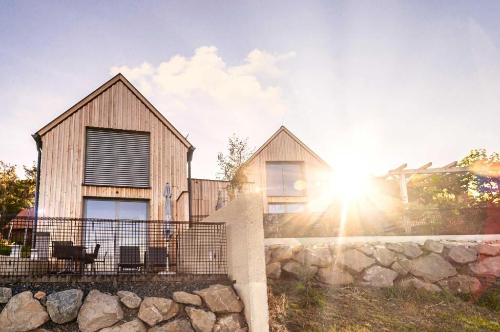 two houses with the sun shining behind them at Weinberg Chalet Klöch in Klöch