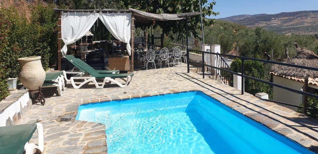 einen blauen Pool mit einem Tisch und Stühlen in der Unterkunft Casa Rural Fuente Zagrilla in Zagrilla