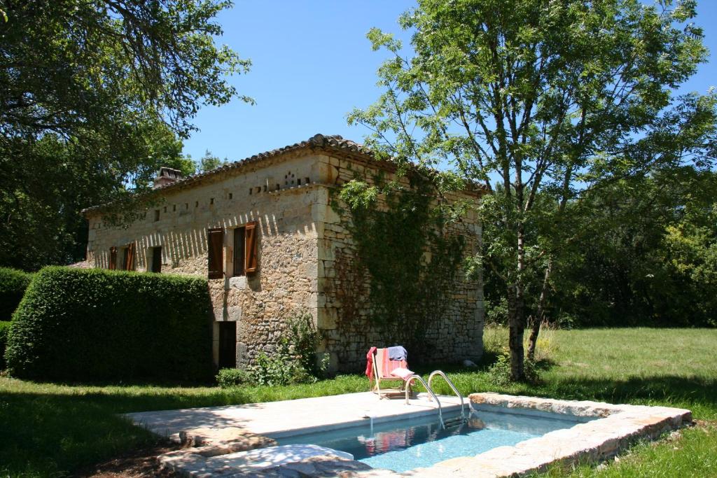 una casa con piscina y una silla frente a ella en Les Gîtes du Mas d'Aspech en Belmont-Sainte-Foi