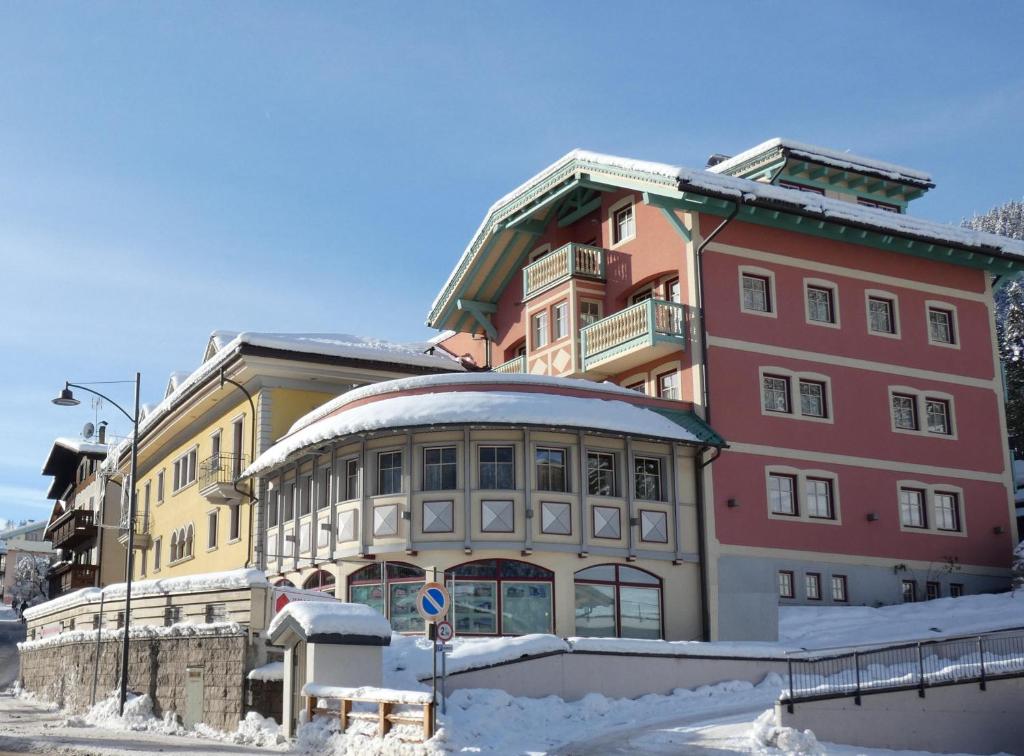 een groot gebouw met sneeuw ervoor bij La Meisules in Pozza di Fassa