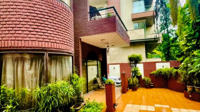 - un grand bâtiment en briques avec un balcon et des plantes dans l'établissement RED BRICK HOME BY EARTHAA ESCAPES, à New Delhi