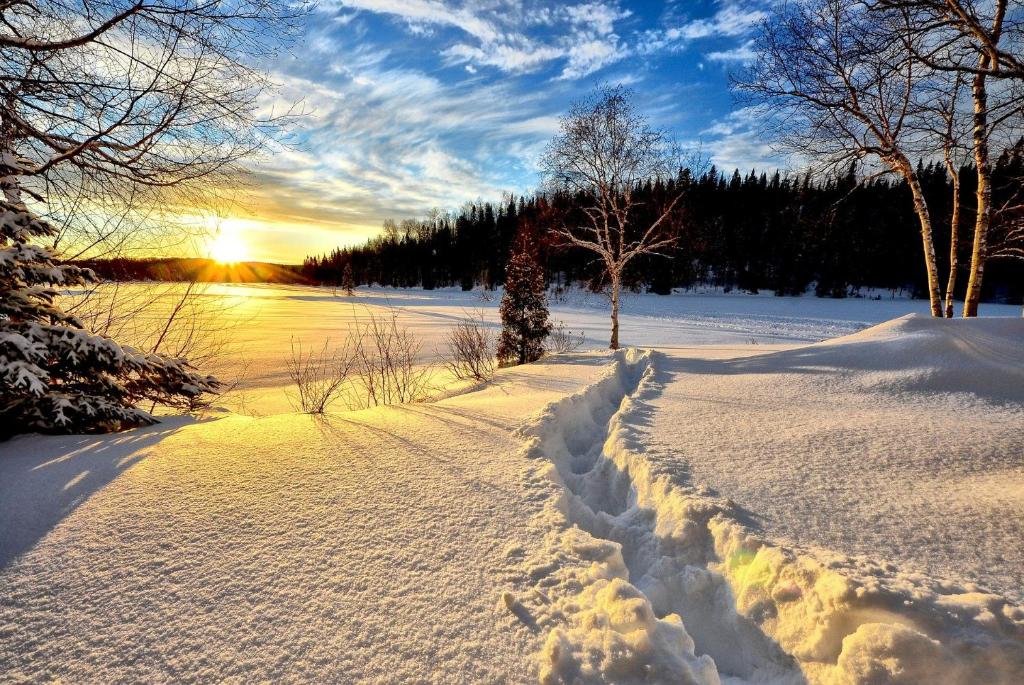 a snow covered road with the sun setting in the background at Gîte Le Grandelinois in Saint-Paulin