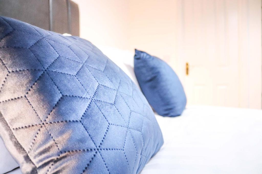 een bed met twee blauwe kussens erop bij Cosy - Modern - Accommodation - In Heart of Northumberland in Newbiggin-by-the-Sea