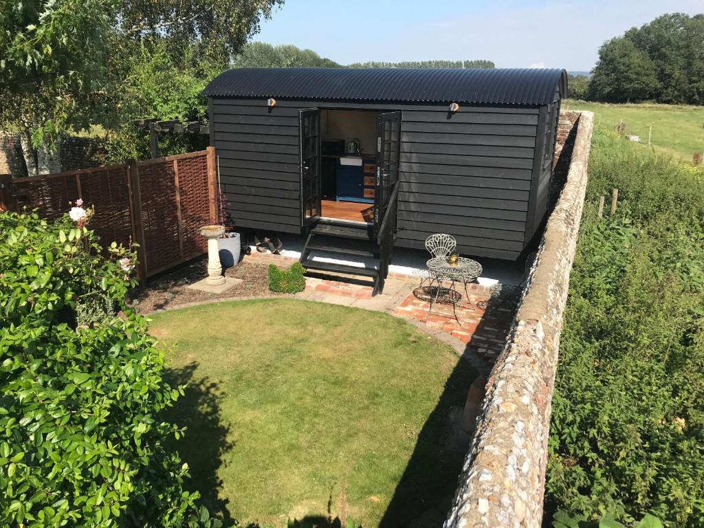 a black tiny house in a garden at Highkettle Hut in Chichester