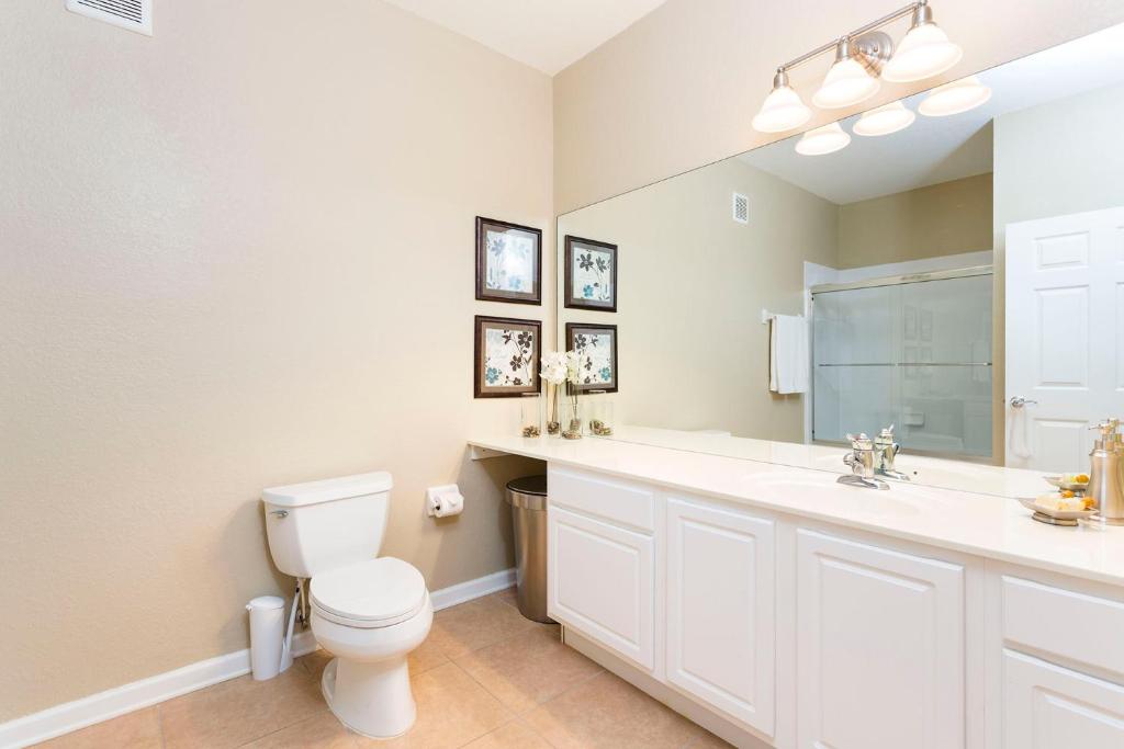 uma casa de banho com um WC, um lavatório e um espelho. em 3Br 2Bath Condo Balcony 5min Conv Center 1388ft em Orlando