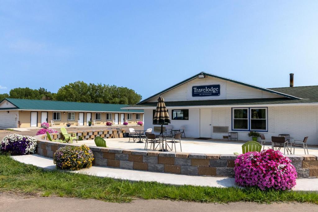 a hotel building with tables and chairs and flowers at Travelodge by Wyndham Spirit Lake/Okoboji in Spirit Lake