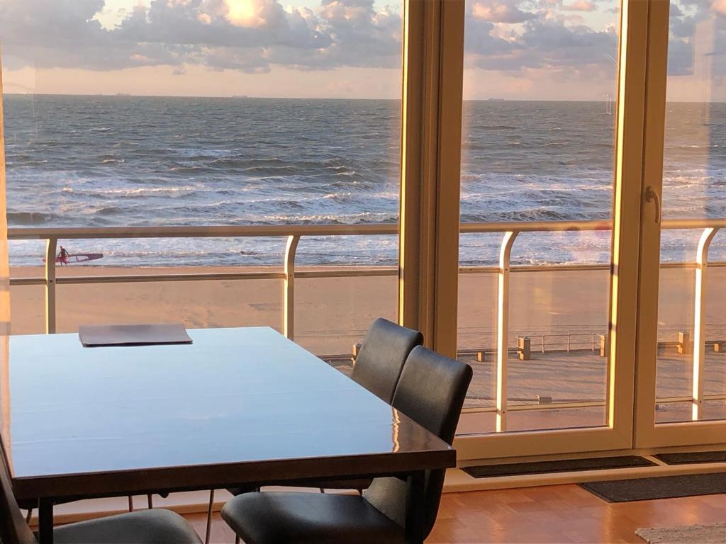 Royal Zeezicht Oostende في أوستند: طاولة وكراسي في غرفة مطلة على المحيط