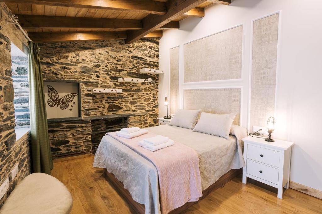 1 dormitorio con cama y pared de piedra en casa boral, en Doade
