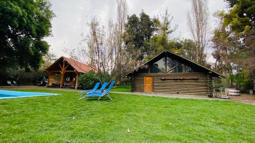 two blue chairs sitting in the grass in front of a cabin at Cabañas Rústicas in Estación Colina