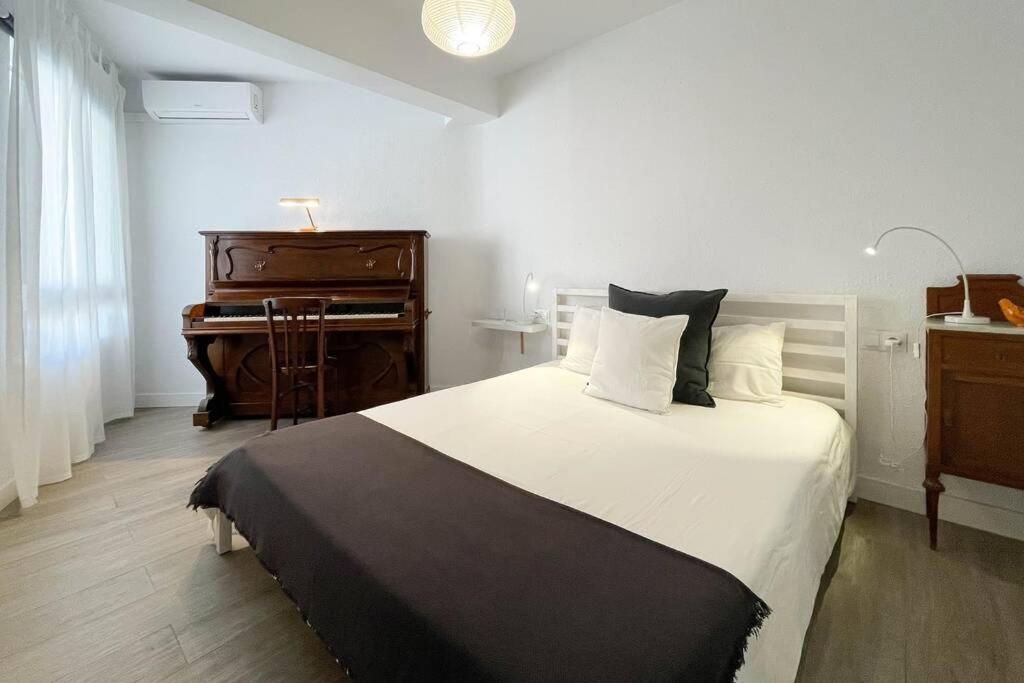 a bedroom with a large bed and a piano at Apartamento con personalidad a 600 m de la playa. in Alicante