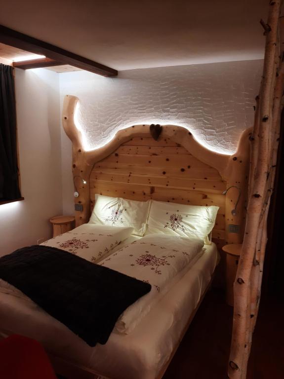 1 dormitorio con cama de madera y cabecero de madera en Appartamento Cirmolo, en Peio