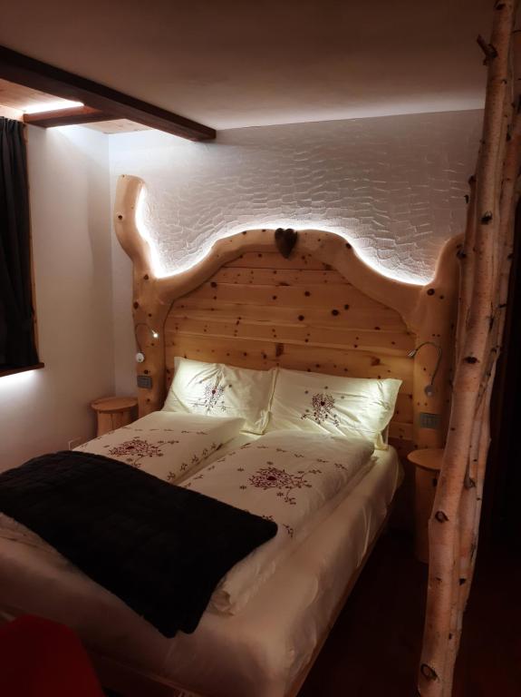a bedroom with a wooden bed with a wooden headboard at Appartamento Cirmolo in Peio