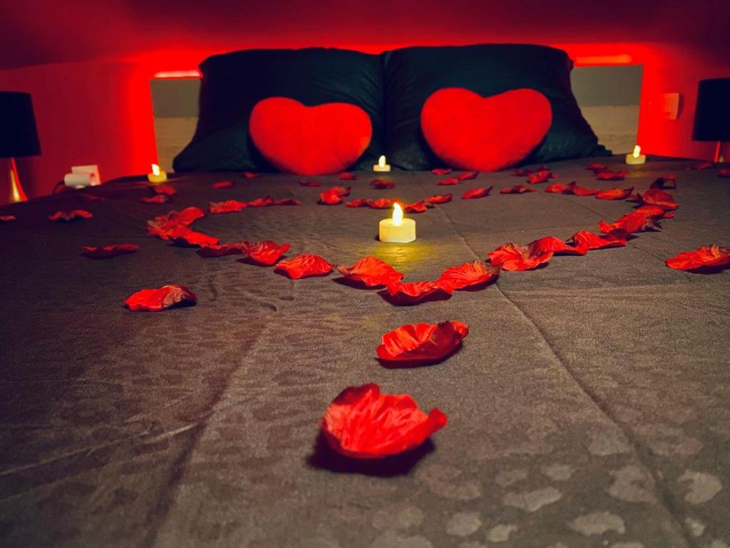 two hearts on a bed with a candle and red roses at La Valentine Spa in Béthisy-Saint-Pierre