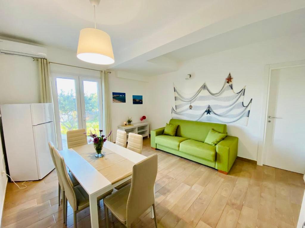 a living room with a table and a green couch at Casa vacanze Almàsalo in Noto Marina