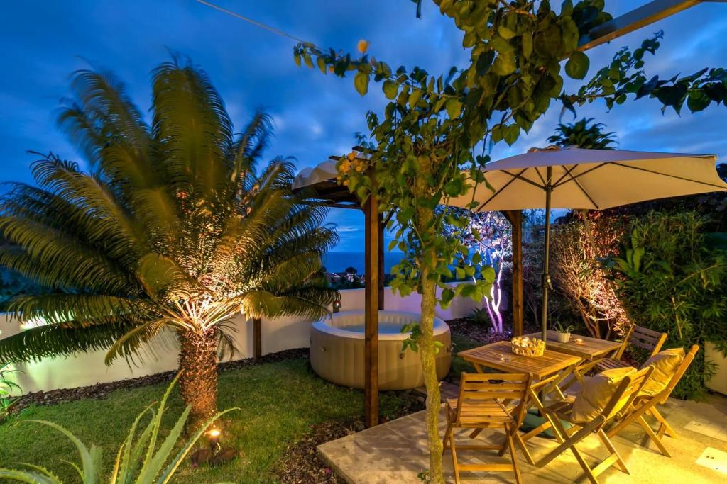 a patio with a table and umbrella and a palm tree at epicenter LAGOA in Lagoa