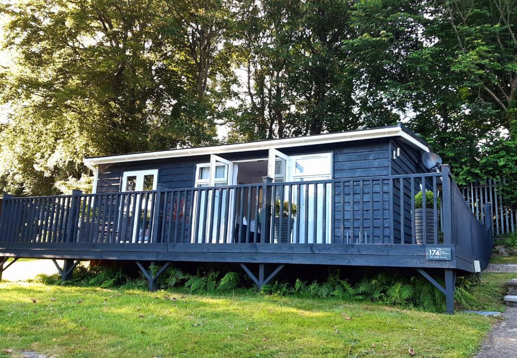 a blue house with a fence in the grass at Chalet 174 Glan Gwna Park Caernarfon in Caeathro