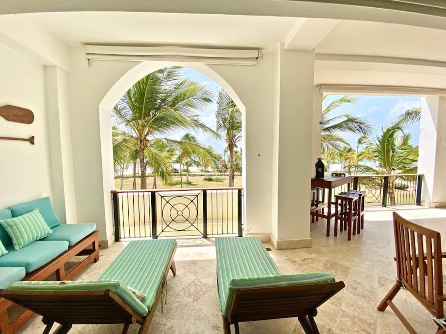 ein Wohnzimmer mit einem Sofa und Stühlen sowie einem Balkon in der Unterkunft Perfect Beach Condo Cap Cana Marina, Punta Cana in Punta Cana