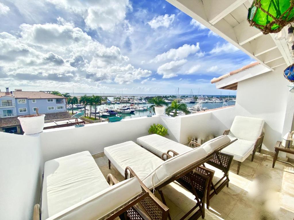 a balcony with white furniture and a view of the harbor at Unique Luxury Pent House At Marina Casa De Campo in La Romana