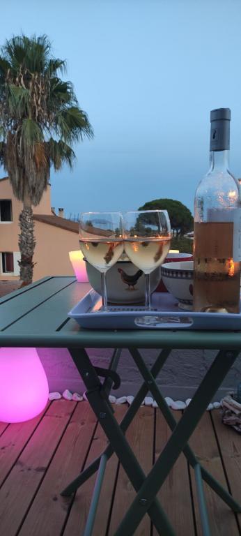 een tafel met twee glazen en een fles wijn bij Suite avec tropezienne vue mer in Hyères