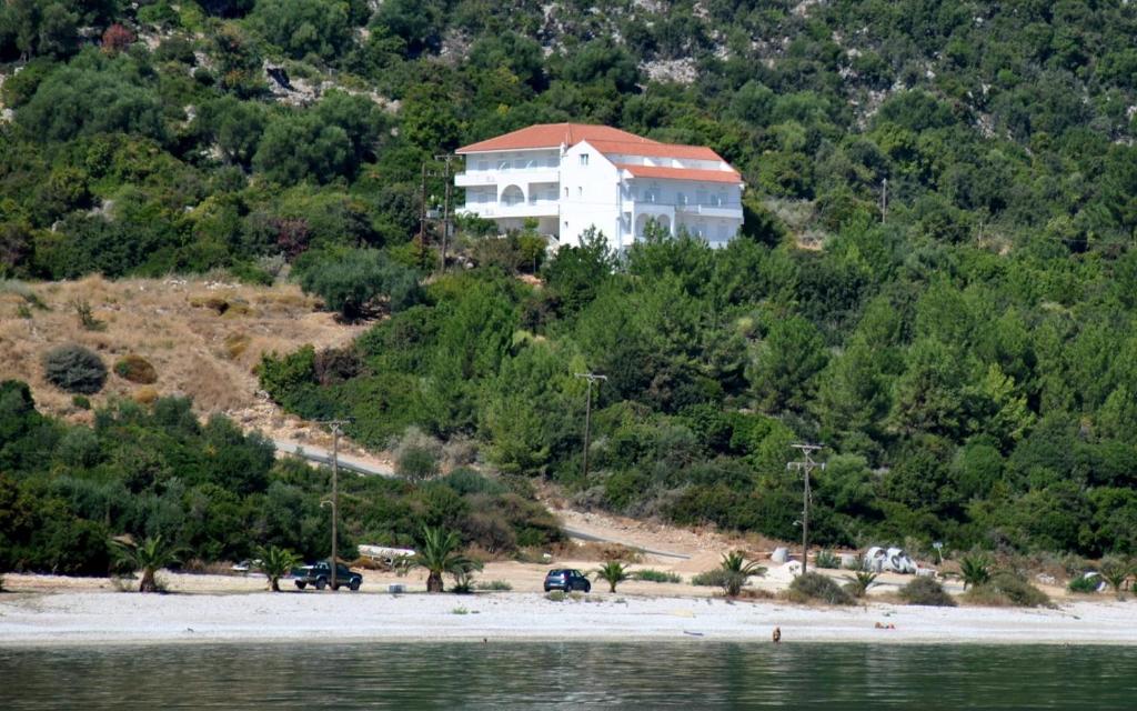 a house on top of a hill next to the water at Filoxenia Hotel & Apartments in Póros Kefalonias
