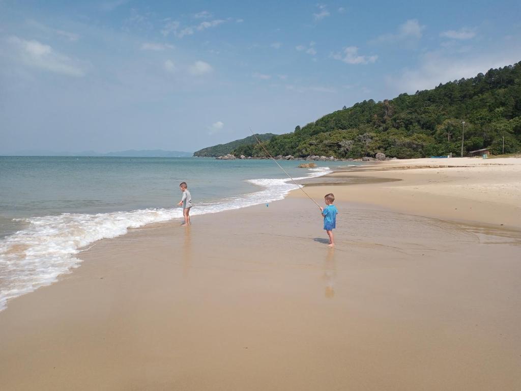 two children standing on a beach flying a kite at Residencial Baía Bela in Bombinhas