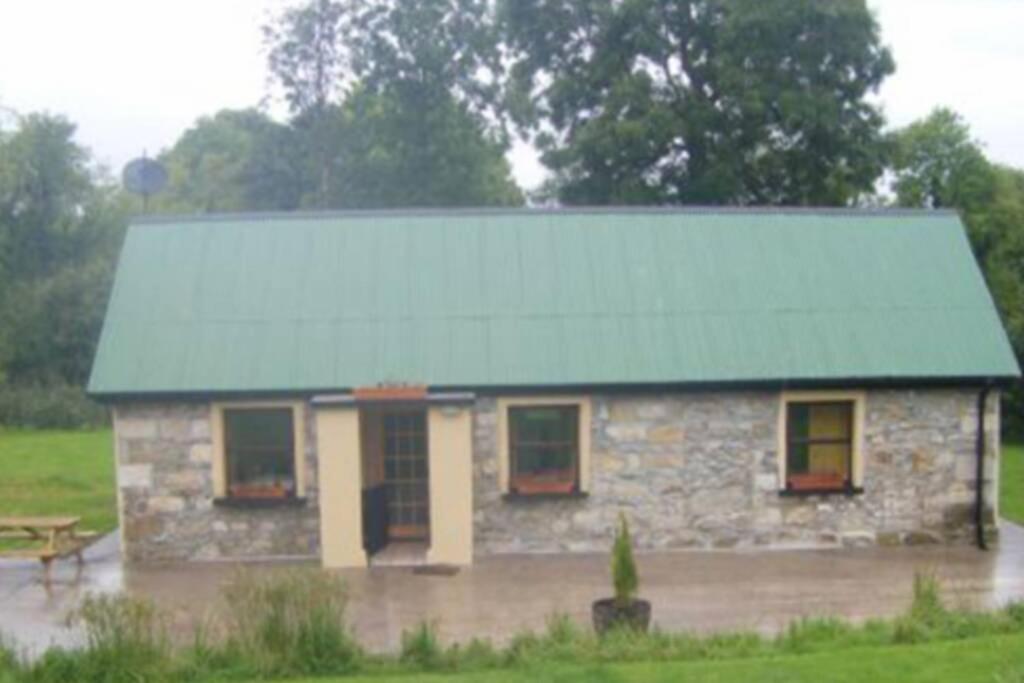 una pequeña casa de piedra con techo verde en Cottage ideal for Family's & private lake access en Leitrim