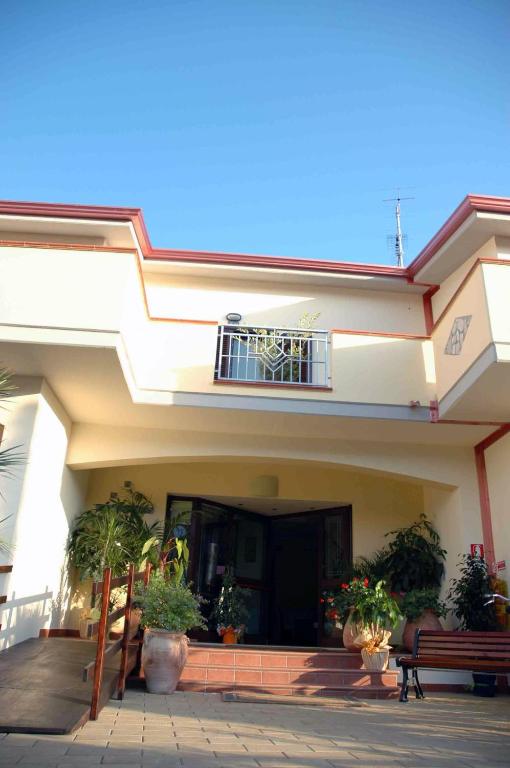 a house with potted plants and a bench in front of it at Hotel Santa Rosa Centro Vacanze in Sangineto