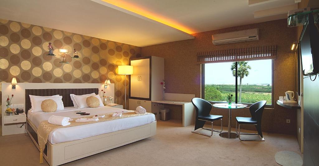 una camera d'albergo con letto, tavolo e sedie di Regency Tuticorin by GRT Hotels a Tuticorin