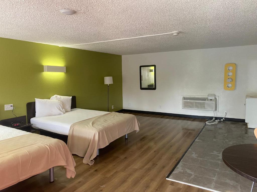 a room with two beds with green walls and wooden floors at MOTEL 9 in Elyria