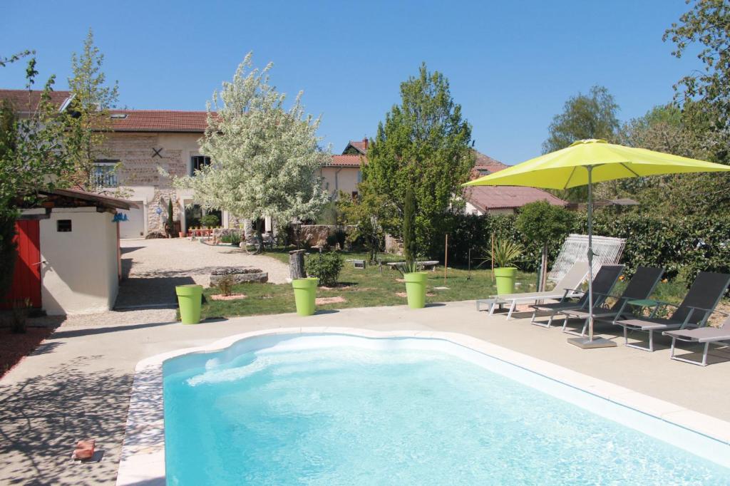 a swimming pool with a yellow umbrella and chairs at Les Trois Maisons in Druillat