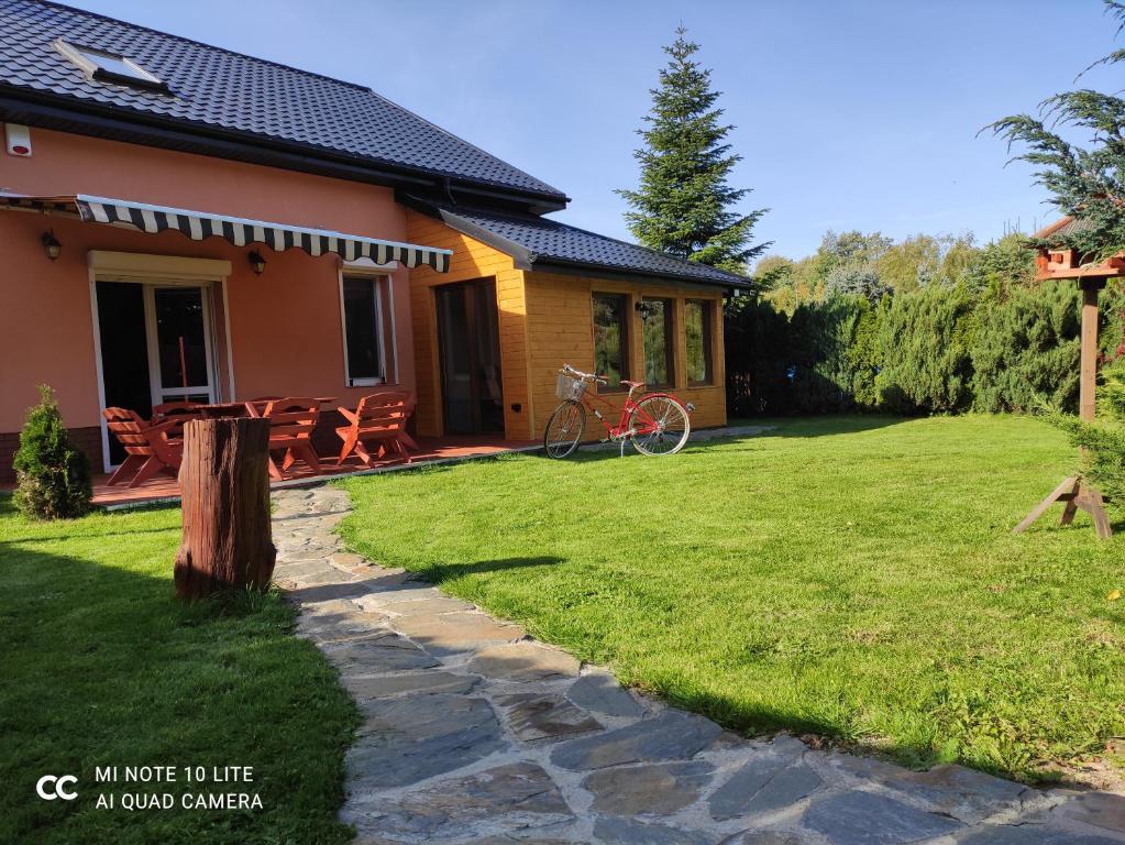 a house with a patio and a grass yard at Miły Domek Sasino in Sasino